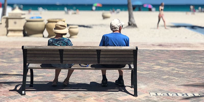 Elderly Couple Sitting in Bench on Beach